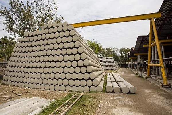 Stacked SPC poles beside a gantry crane at the PCL yard